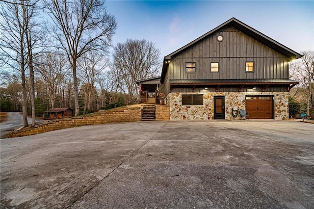 view of front of property with an attached garage, driveway, stairway, and board and batten siding