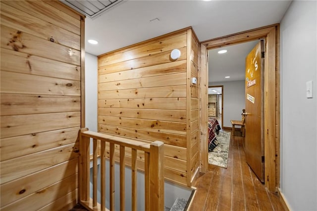 hallway featuring wood walls, wood finished floors, and recessed lighting