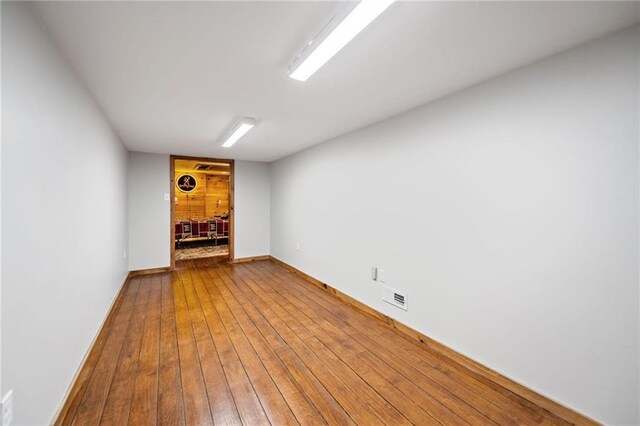 unfurnished room featuring baseboards, visible vents, and wood finished floors