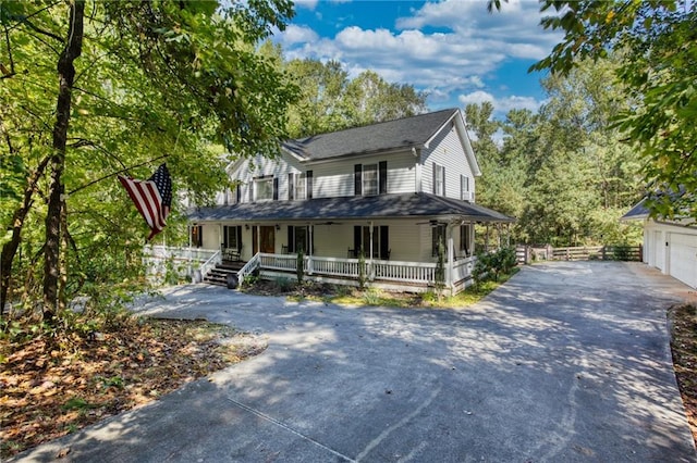 farmhouse inspired home featuring covered porch, an outdoor structure, and a garage