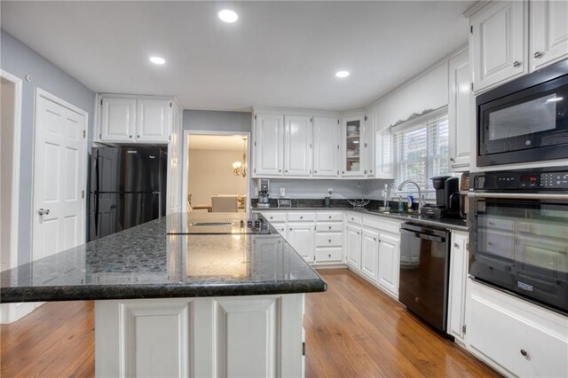 kitchen with black appliances, a kitchen island, and white cabinets