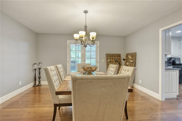 dining space with light hardwood / wood-style floors and an inviting chandelier