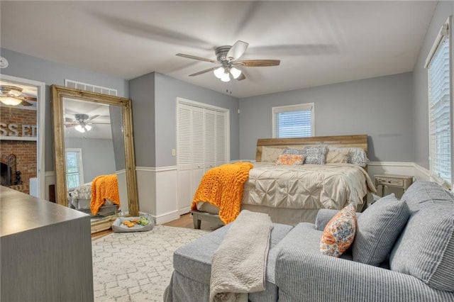 bedroom with a closet, ceiling fan, a fireplace, and hardwood / wood-style floors