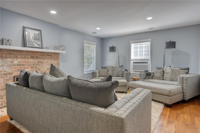 living room featuring hardwood / wood-style floors, a brick fireplace, and a healthy amount of sunlight