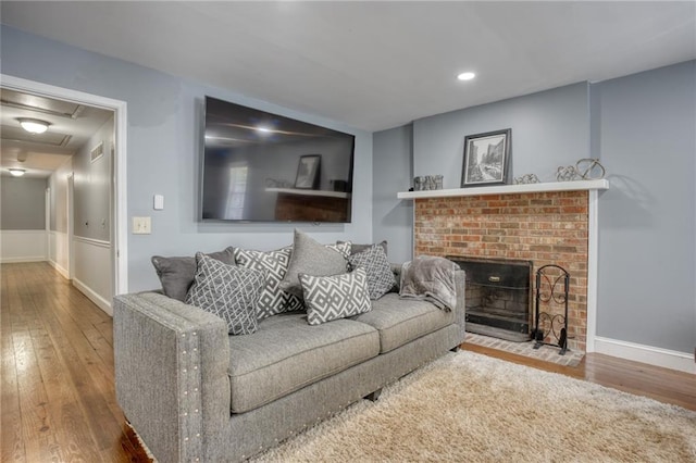 living room featuring hardwood / wood-style flooring and a brick fireplace