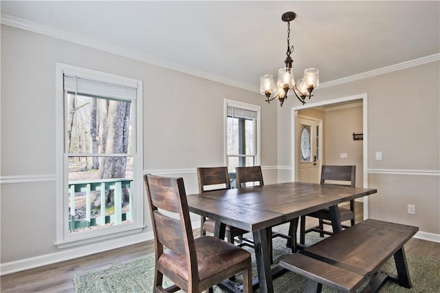 dining space with an inviting chandelier, crown molding, wood finished floors, and baseboards