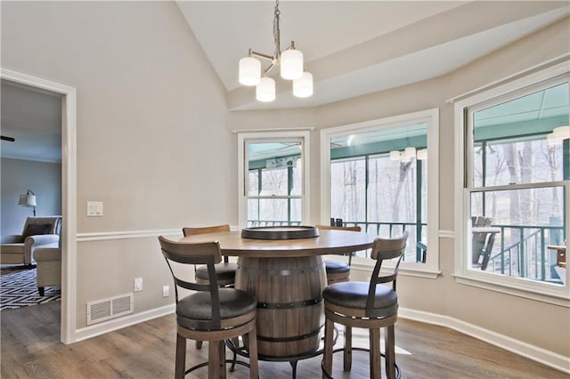 dining room featuring visible vents, baseboards, wood finished floors, and vaulted ceiling