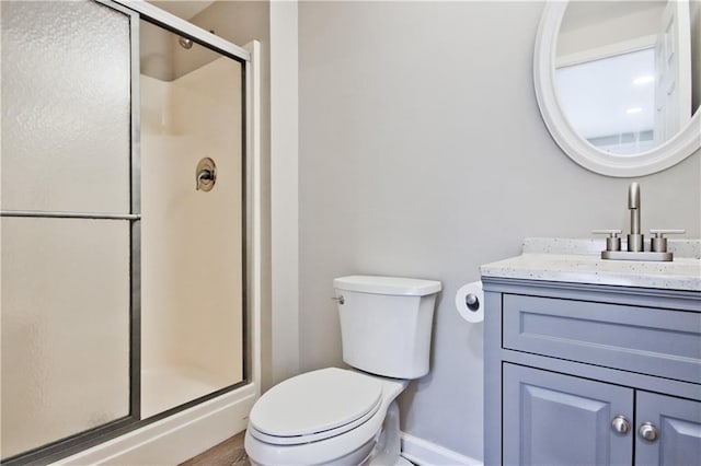 bathroom with vanity, toilet, baseboards, and a stall shower