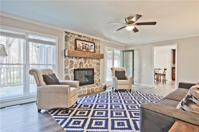 living area featuring a fireplace, wood finished floors, baseboards, and ornamental molding