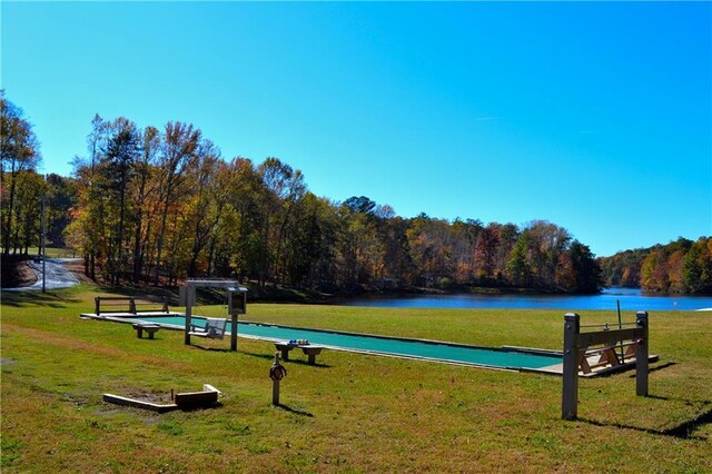 surrounding community with a yard, a water view, and a view of trees