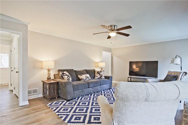 living room with visible vents, wood finished floors, crown molding, baseboards, and ceiling fan