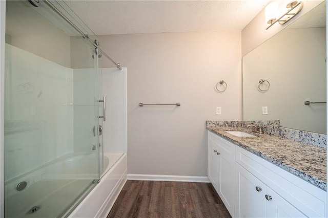 bathroom featuring vanity, hardwood / wood-style floors, enclosed tub / shower combo, and a textured ceiling