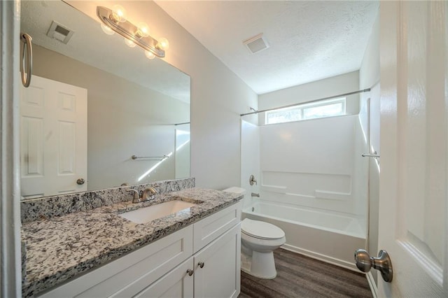 full bathroom featuring hardwood / wood-style floors, vanity, a textured ceiling, shower / bathtub combination, and toilet