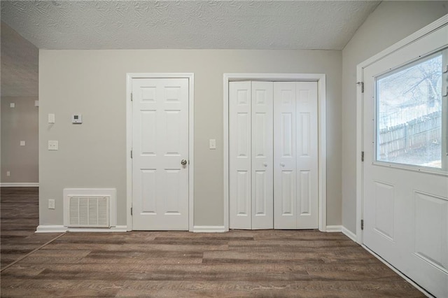 foyer entrance with dark wood-type flooring and a textured ceiling