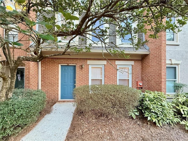 view of exterior entry featuring brick siding and a shingled roof