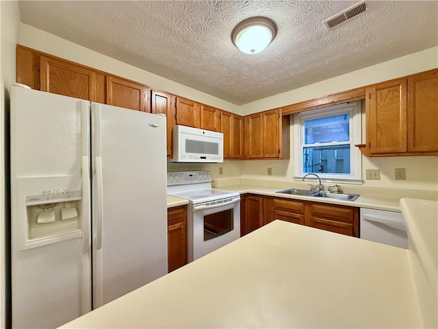 kitchen featuring light countertops, white appliances, a sink, and visible vents