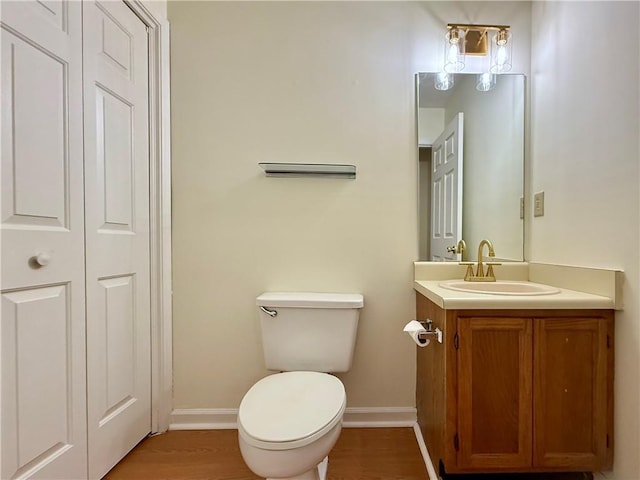 bathroom with toilet, baseboards, wood finished floors, and vanity