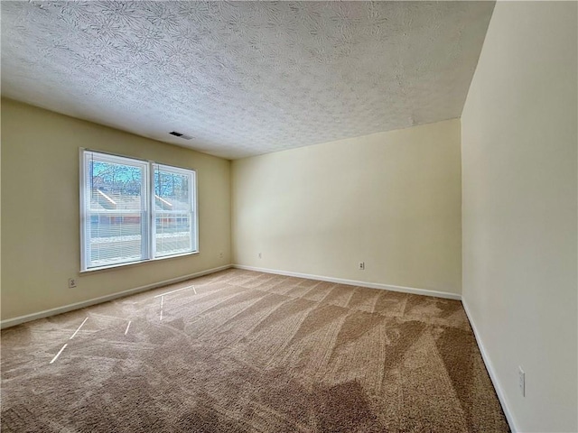 unfurnished room with visible vents, carpet flooring, a textured ceiling, and baseboards