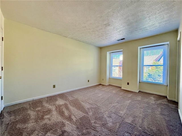 carpeted empty room with a textured ceiling, visible vents, and baseboards