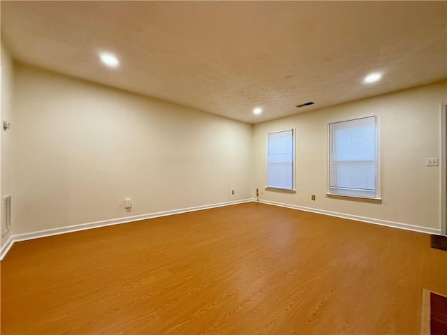 empty room with visible vents, baseboards, wood finished floors, and recessed lighting