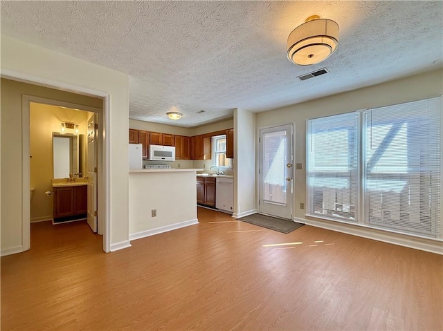 kitchen featuring white appliances, visible vents, dark wood-style flooring, light countertops, and a sink