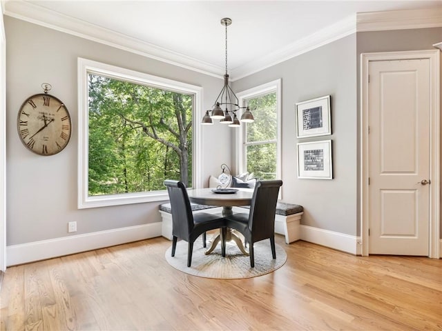 dining space featuring crown molding, a healthy amount of sunlight, a chandelier, and light hardwood / wood-style floors