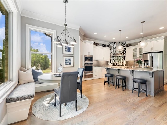 dining room with breakfast area, an inviting chandelier, crown molding, and light hardwood / wood-style floors