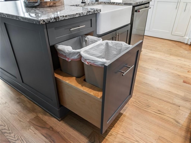 details featuring stone countertops, a center island, sink, and light wood-type flooring