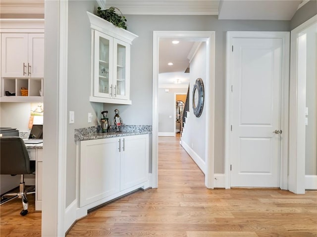 bar featuring white cabinetry, light stone countertops, ornamental molding, and light hardwood / wood-style floors