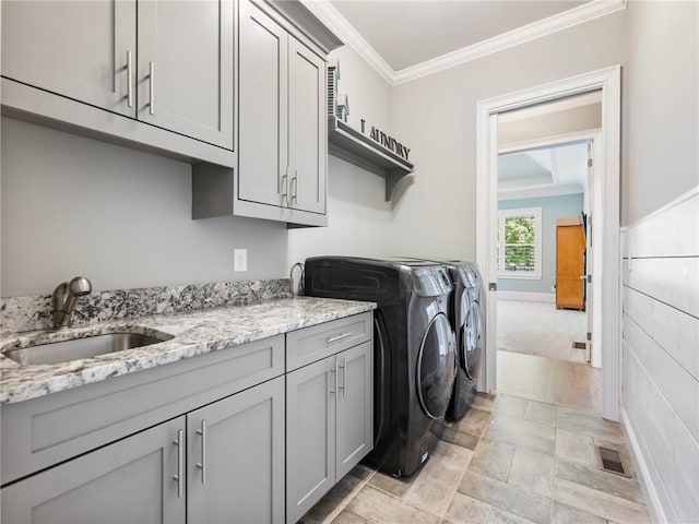 laundry area featuring crown molding, cabinets, sink, and washing machine and clothes dryer