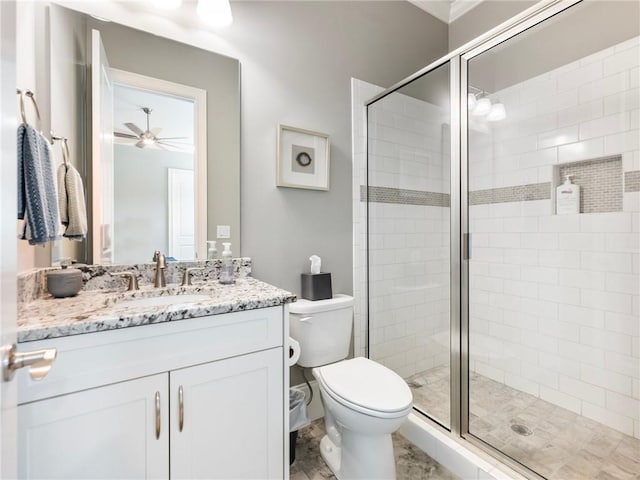 bathroom with a shower with door, vanity, ceiling fan, and toilet