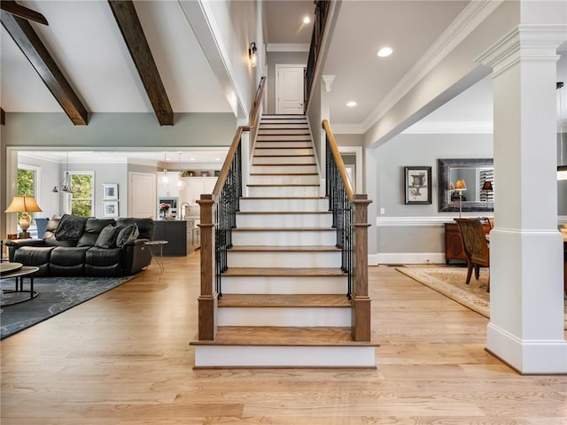 staircase featuring decorative columns, crown molding, hardwood / wood-style floors, and beam ceiling