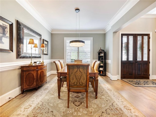 dining area with ornamental molding and light hardwood / wood-style floors