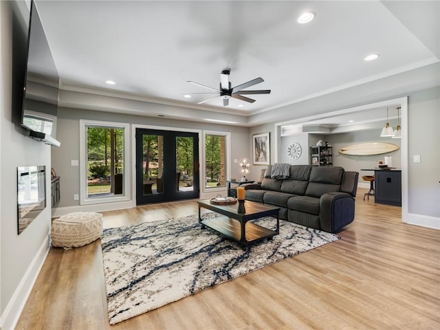 living room with crown molding, ceiling fan, light wood-type flooring, and french doors