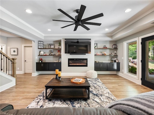 living room with ceiling fan, ornamental molding, and light hardwood / wood-style floors