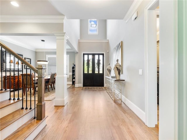 entryway featuring ornamental molding, light hardwood / wood-style flooring, and ornate columns