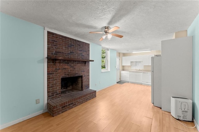 185 Lee Path, Acworth, GA 30102 - unfurnished living room with a ceiling fan, light wood-type flooring, a textured ceiling, and a brick fireplace