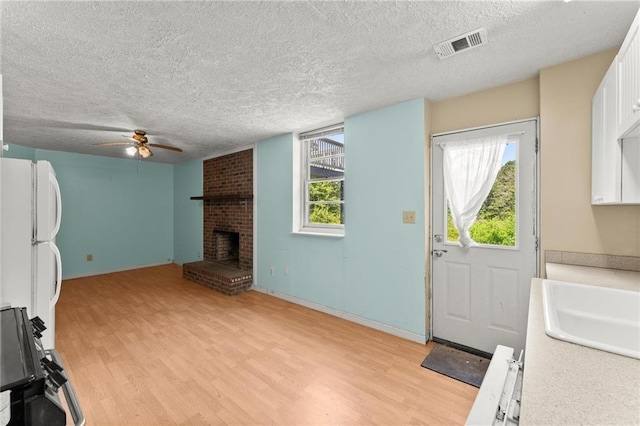 185 Lee Path, Acworth, GA 30102 - kitchen with light wood-style flooring, stove, a textured ceiling, a fireplace, and a ceiling fan