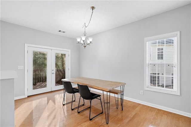 dining room featuring a chandelier, light wood-type flooring, and french doors