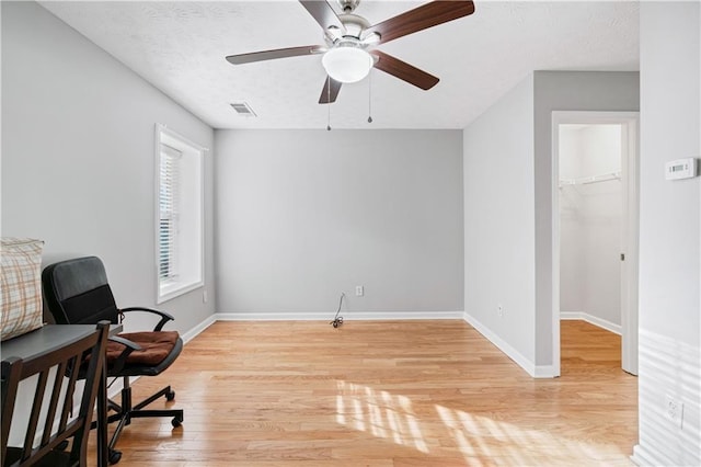 living area with ceiling fan, a textured ceiling, and light wood-type flooring