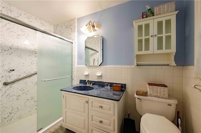 bathroom featuring vanity, toilet, walk in shower, and tile walls