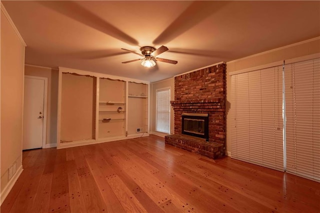 unfurnished living room with a fireplace, crown molding, hardwood / wood-style floors, and ceiling fan