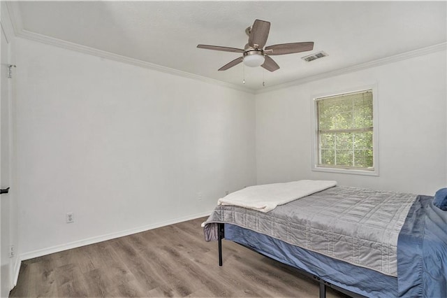 bedroom featuring ornamental molding, visible vents, and wood finished floors