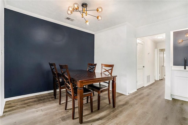 dining room with ornamental molding, a chandelier, visible vents, and wood finished floors