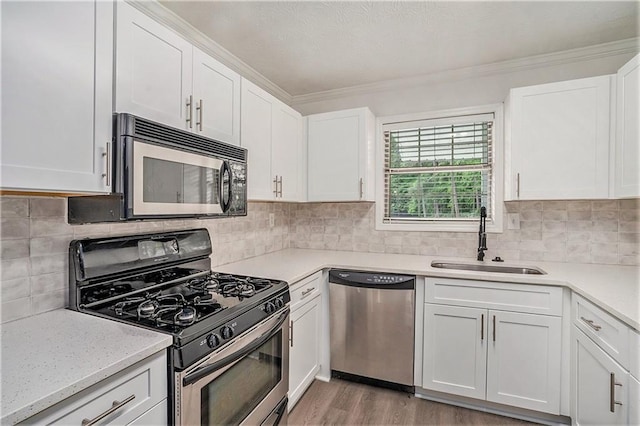 kitchen featuring a sink, white cabinetry, light countertops, and appliances with stainless steel finishes