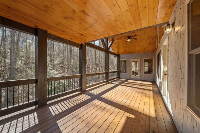 unfurnished sunroom featuring wood ceiling, a ceiling fan, vaulted ceiling, and a wealth of natural light