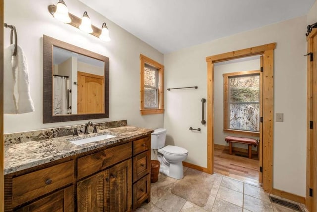 bathroom featuring toilet, vanity, visible vents, baseboards, and tile patterned floors