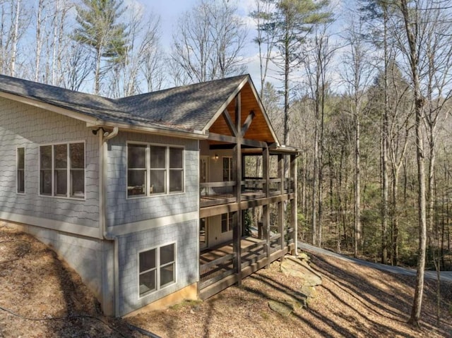 view of side of home with roof with shingles