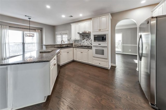 kitchen featuring pendant lighting, stainless steel appliances, kitchen peninsula, and white cabinets