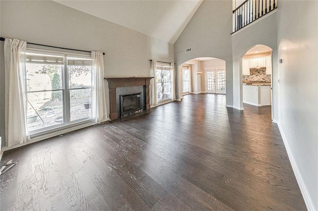 unfurnished living room with high vaulted ceiling and dark hardwood / wood-style flooring